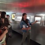 Grupa osób słucha kobiety oprowadzającej po wystawie w muzeum